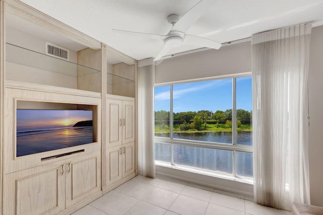 unfurnished living room featuring a water view, ceiling fan, and light tile patterned floors