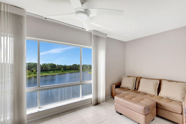 living room featuring a water view, ceiling fan, and light tile patterned floors