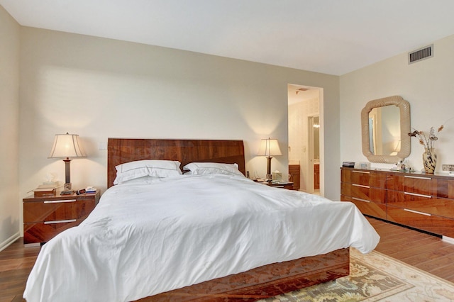 bedroom with visible vents, baseboards, and wood finished floors