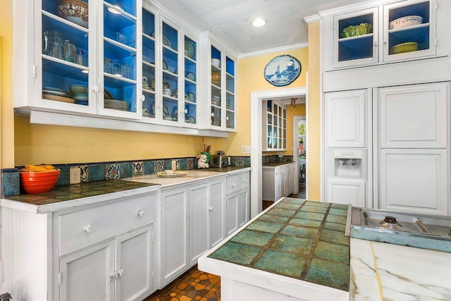 kitchen featuring white cabinetry, crown molding, and dark tile patterned floors