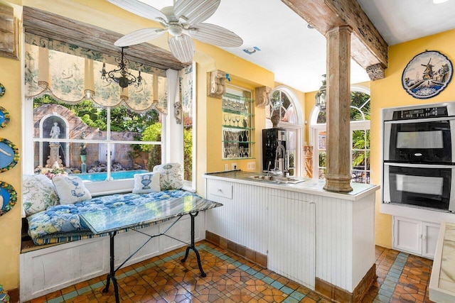 kitchen with ornate columns, white cabinetry, sink, kitchen peninsula, and double oven