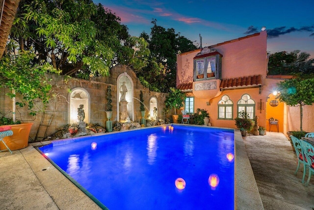 pool at dusk featuring a patio area