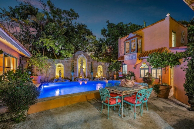 pool at night featuring a patio