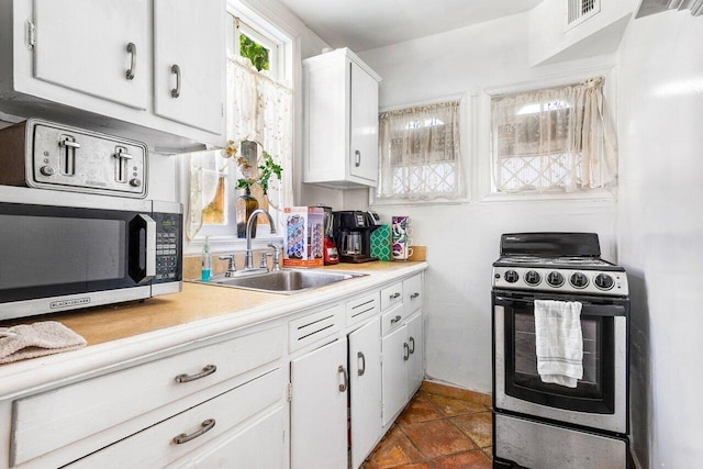 kitchen featuring sink, dark tile patterned flooring, white cabinetry, and stainless steel appliances