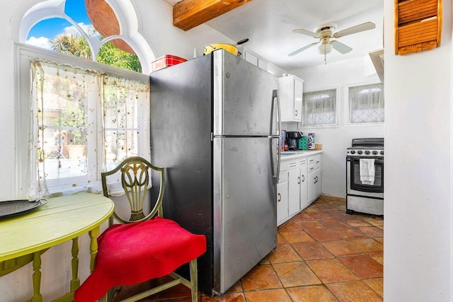 kitchen with beamed ceiling, appliances with stainless steel finishes, tile patterned floors, ceiling fan, and white cabinets