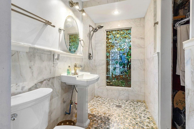 bathroom with tile walls, a tile shower, and toilet