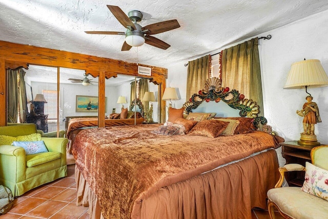 bedroom with ceiling fan, a textured ceiling, and tile patterned floors