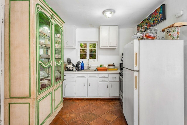 kitchen with dark tile patterned flooring, white cabinetry, and white refrigerator