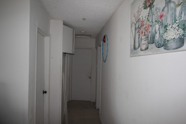 corridor with a textured ceiling and tile patterned floors