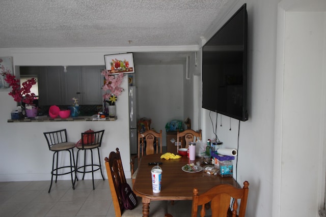 dining area with a textured ceiling and light tile patterned flooring