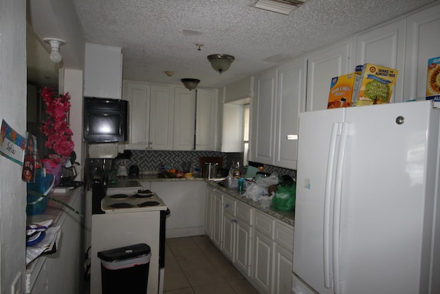 kitchen featuring white refrigerator, white cabinetry, light tile patterned flooring, and decorative backsplash