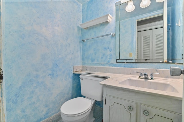 bathroom with vanity, toilet, and wallpapered walls