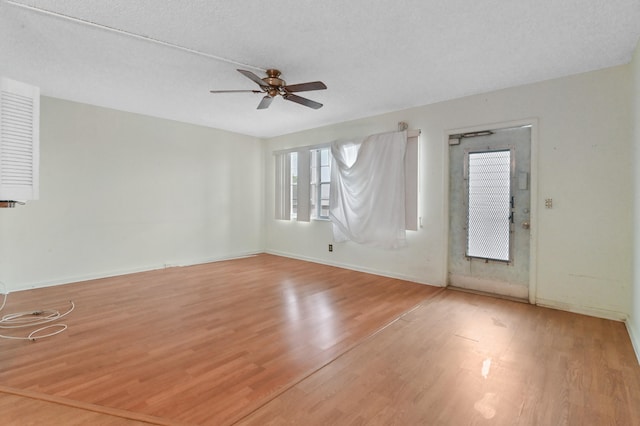 unfurnished room with ceiling fan, a textured ceiling, wood finished floors, and baseboards