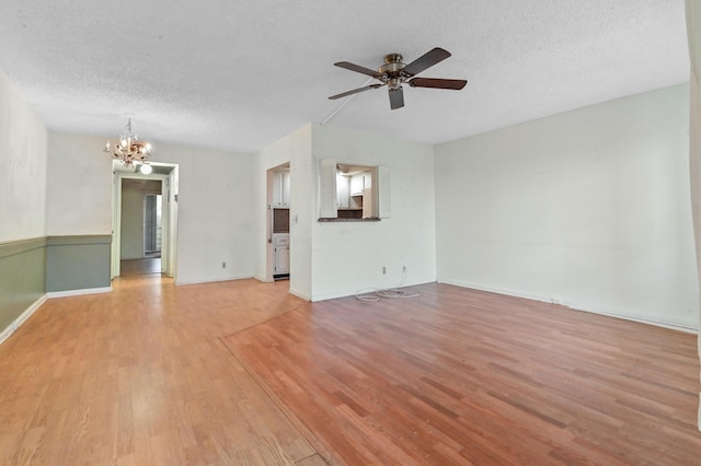 unfurnished living room featuring light wood-style floors, baseboards, ceiling fan with notable chandelier, and a textured ceiling
