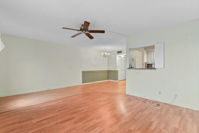 unfurnished living room featuring ceiling fan with notable chandelier, visible vents, a textured ceiling, and light wood-style flooring