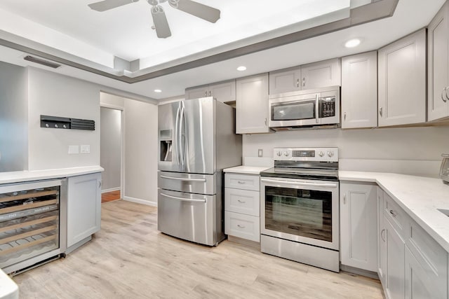 kitchen featuring stainless steel appliances, light hardwood / wood-style floors, wine cooler, ceiling fan, and gray cabinets