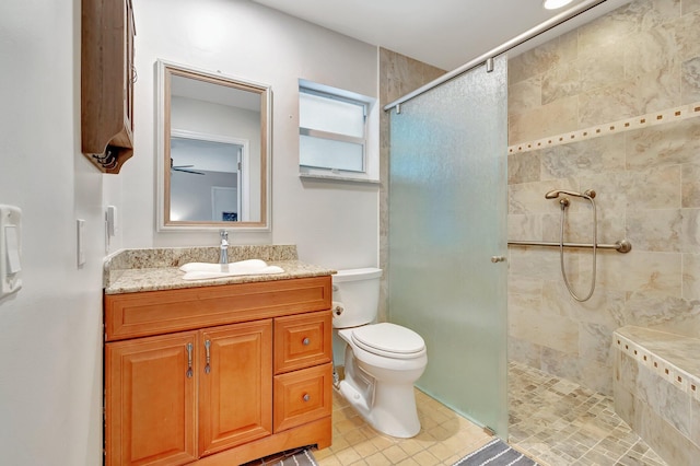 bathroom with tile patterned flooring, tiled shower, toilet, and vanity