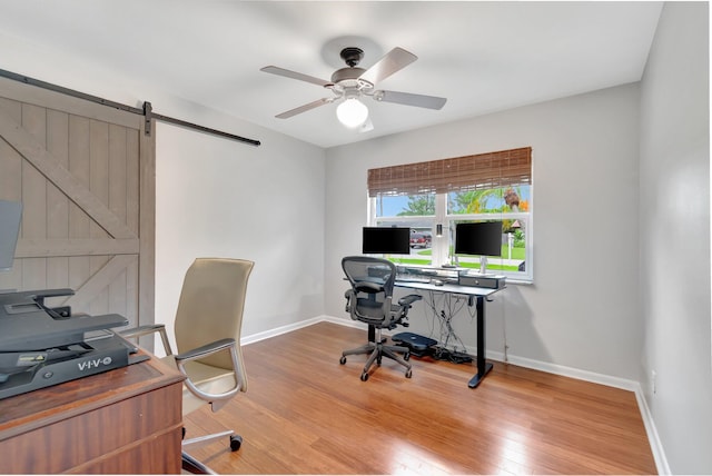 office space with light wood-type flooring, a barn door, and ceiling fan