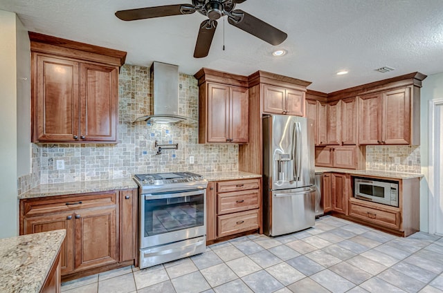 kitchen featuring appliances with stainless steel finishes, backsplash, wall chimney exhaust hood, light tile patterned floors, and ceiling fan