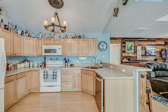 kitchen featuring wood walls, light hardwood / wood-style floors, sink, a textured ceiling, and white appliances