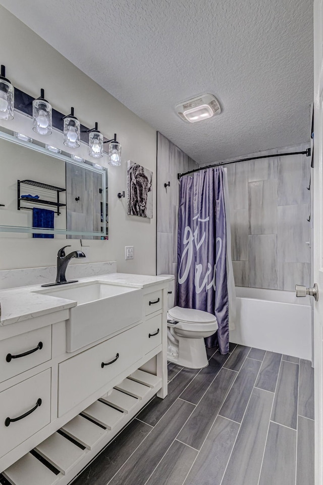 full bathroom featuring shower / bath combo with shower curtain, a textured ceiling, vanity, and toilet