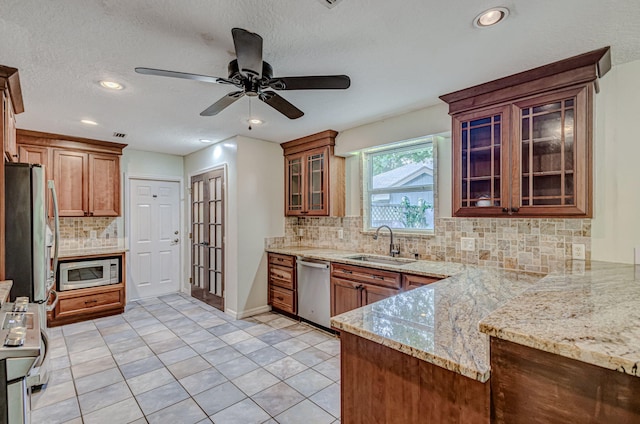 kitchen with ceiling fan, backsplash, light stone counters, sink, and stainless steel appliances