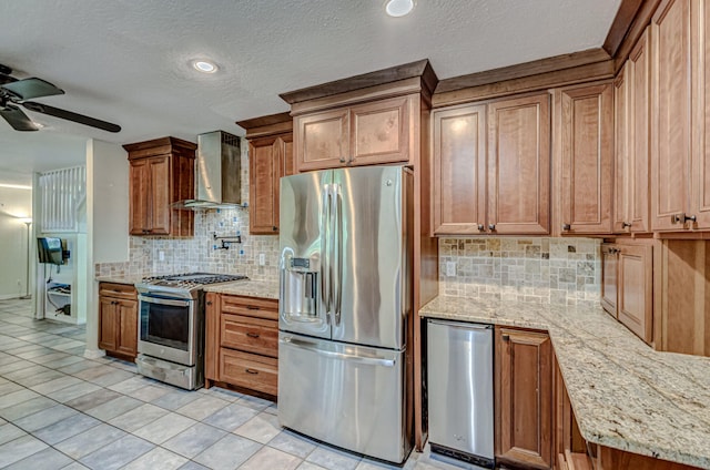 kitchen featuring light tile patterned flooring, appliances with stainless steel finishes, wall chimney exhaust hood, tasteful backsplash, and ceiling fan