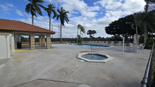 view of swimming pool featuring a hot tub and a patio area