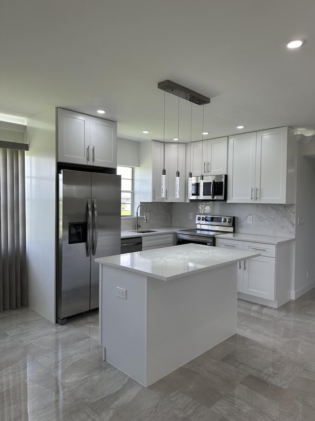 kitchen with stainless steel appliances, a kitchen island, a sink, white cabinetry, and hanging light fixtures