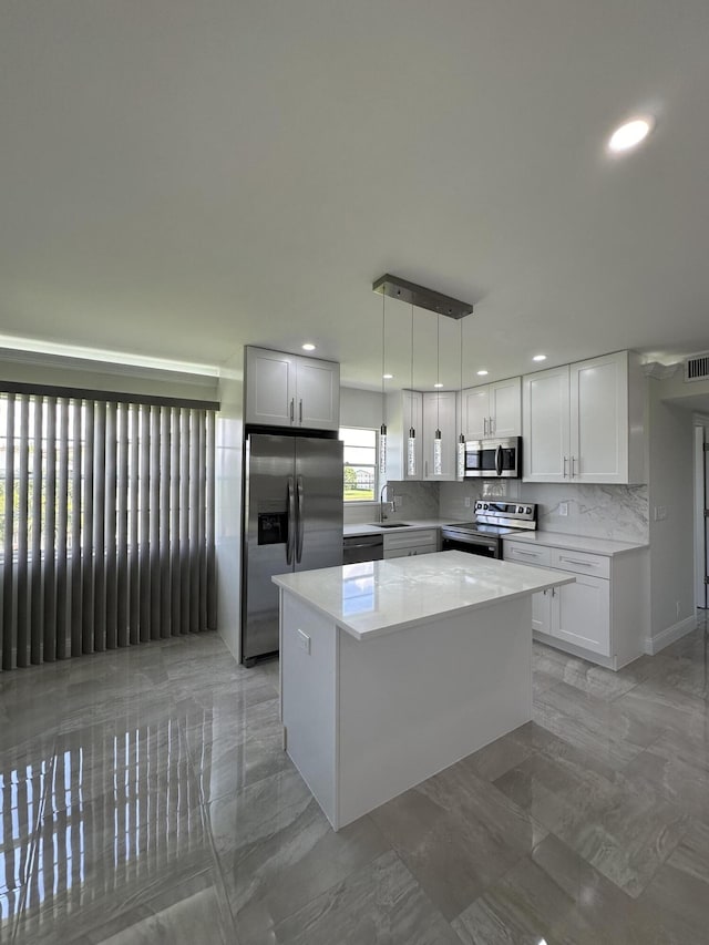 kitchen featuring pendant lighting, marble finish floor, appliances with stainless steel finishes, white cabinets, and a kitchen island