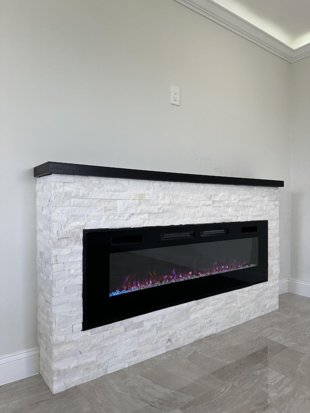 interior details with baseboards, ornamental molding, and a stone fireplace