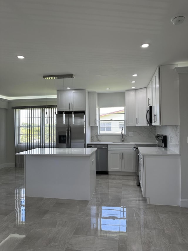 kitchen featuring stainless steel appliances, a sink, white cabinets, hanging light fixtures, and light countertops