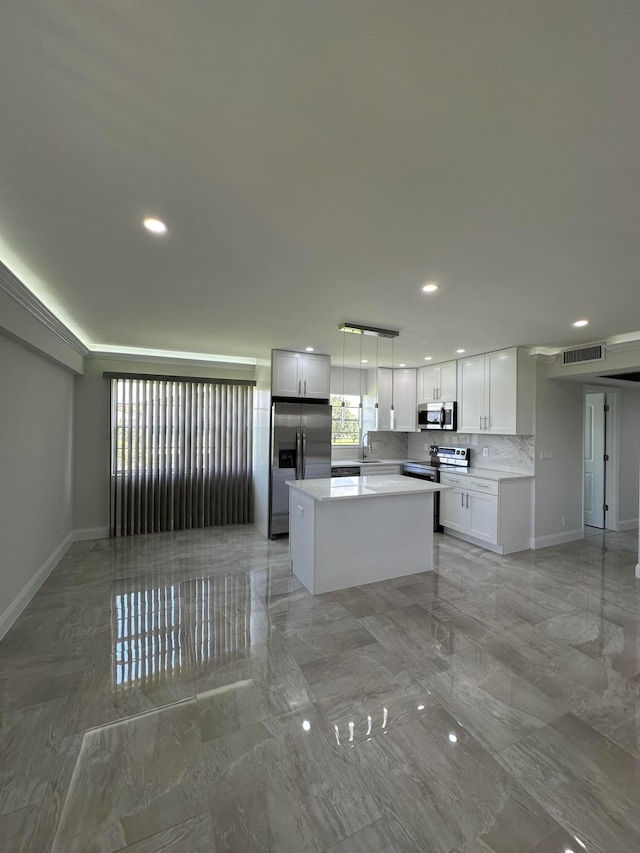 kitchen featuring light tile patterned floors, a center island, appliances with stainless steel finishes, white cabinets, and decorative light fixtures