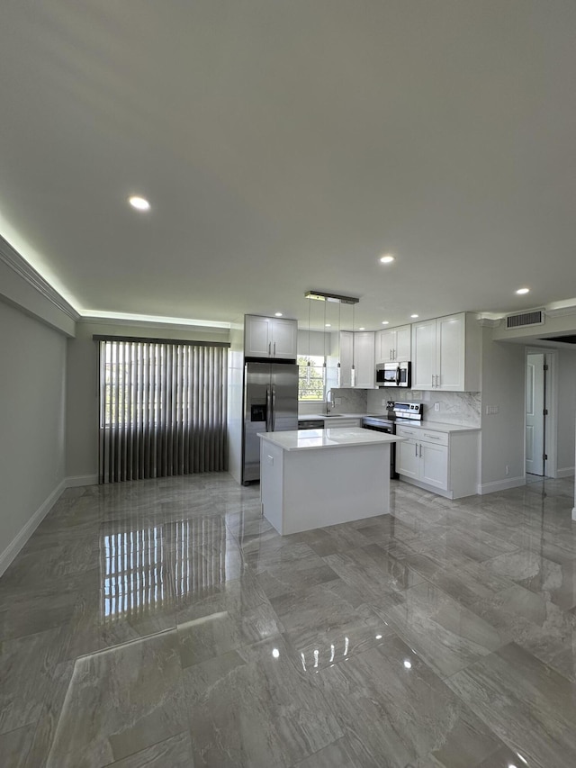 kitchen with pendant lighting, light countertops, appliances with stainless steel finishes, white cabinetry, and a kitchen island