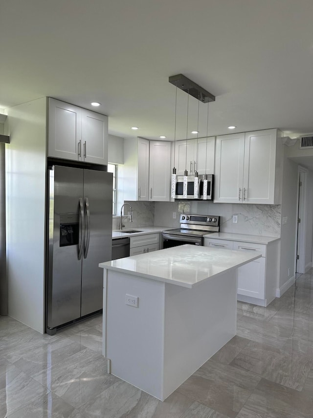 kitchen featuring appliances with stainless steel finishes, white cabinets, pendant lighting, and a kitchen island