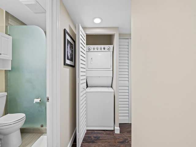 bathroom with toilet, stacked washer / drying machine, and wood-type flooring