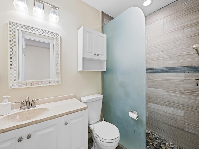 bathroom featuring vanity, toilet, and tiled shower