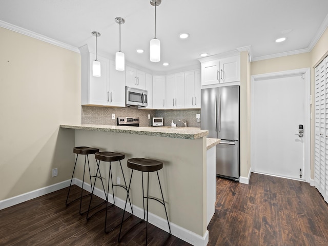 kitchen with stainless steel appliances, kitchen peninsula, hanging light fixtures, and white cabinets