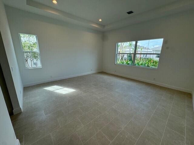 unfurnished room with a healthy amount of sunlight and a tray ceiling