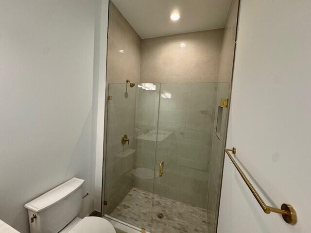 bathroom with a shower with door and toilet