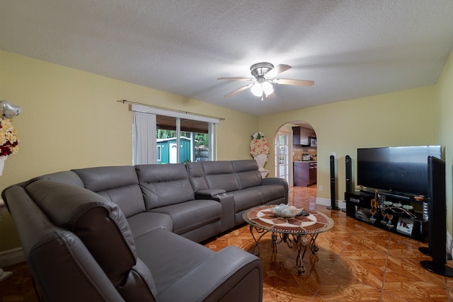 living room featuring ceiling fan, a textured ceiling, and parquet flooring