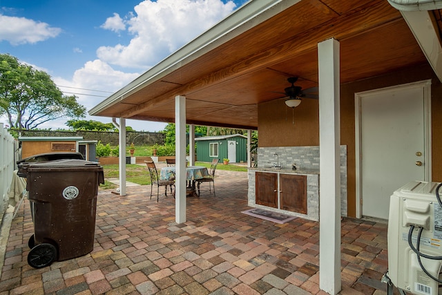 view of patio / terrace with ceiling fan, a storage shed, washer / dryer, and sink