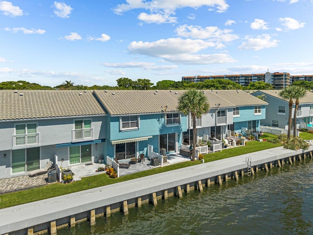 back of house featuring a patio, a balcony, and a water view