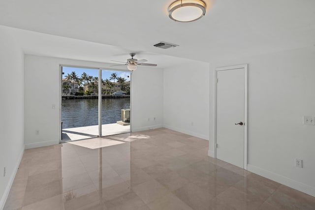 tiled spare room featuring ceiling fan and a water view