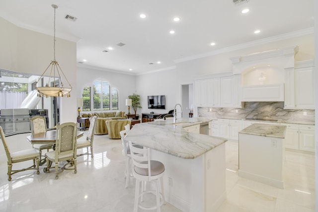 kitchen featuring light stone countertops, decorative backsplash, a kitchen island, white cabinetry, and hanging light fixtures