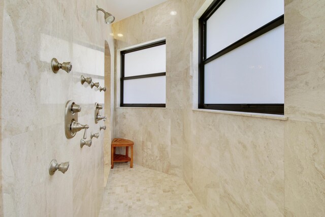 bathroom featuring tiled shower and tile walls