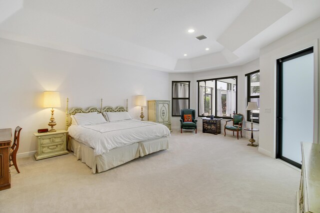 carpeted bedroom with access to exterior and a raised ceiling