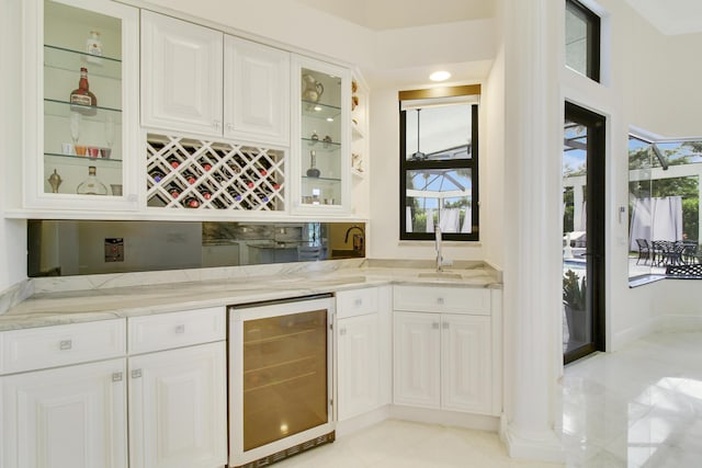 bar featuring white cabinets, light stone counters, sink, and wine cooler