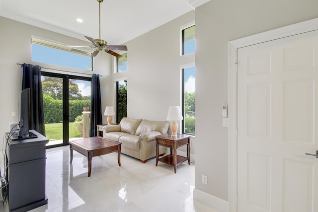 living room with a high ceiling, ceiling fan, and ornamental molding