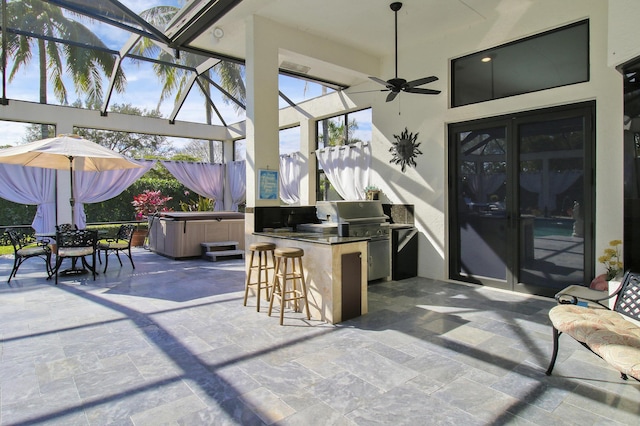 view of patio / terrace with glass enclosure, ceiling fan, a grill, a bar, and a hot tub